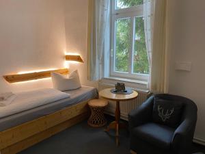 ein kleines Zimmer mit einem Bett, einem Stuhl und einem Fenster in der Unterkunft Pension Schmidt in Schierke