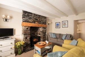 a living room with a stone fireplace and a couch at Homelands in Port Isaac