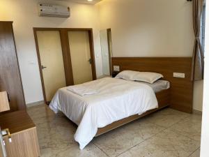 a bedroom with a large bed with white sheets at Sansav Garden Resort in Gurpur +38 photos