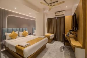 a bedroom with a bed and a desk and a television at Hotel Malad Inn opposite Malad Railway Station in Mumbai +77 photos