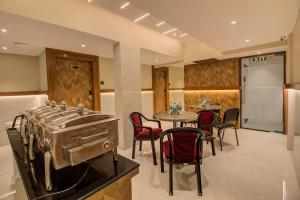 a kitchen with a stove and a table with chairs at Hotel Malad Inn opposite Malad Railway Station in Mumbai