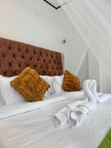 a white bed with white sheets and brown pillows at Oasis Peak Ella in Ella