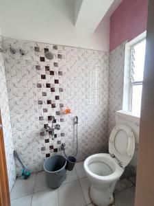 a bathroom with a toilet and a bucket at OhanaStay02 in Guwahati +5 photos