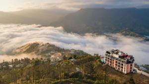 a building on top of a mountain with clouds at DeLaMont Sapa Hotel - Hill Serenity Retreat in Sapa