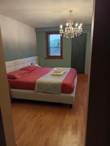 a bedroom with a bed with red sheets and a chandelier at Dolomitiloungebelluno Mountain Stay in Belluno