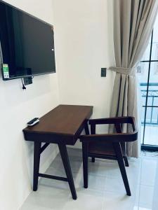 a desk with a chair and a television on a wall at GreenHotel in Ban M'drack