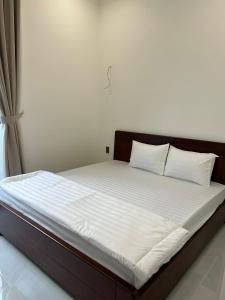 a bed with white sheets and pillows in a room at GreenHotel in Ban M'drack