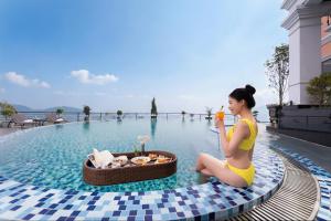 a woman sitting on the edge of a pool with a drink at DeLaMont Sapa Hotel - Hill Serenity Retreat in Sapa +104 photos