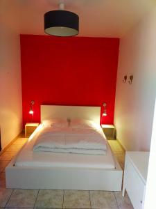 a bedroom with a red wall and a white bed at Houlgate T2 bis in Houlgate