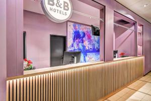 a bar in a restaurant with purple walls at B&B HOTEL Kassel-Wilhelmshöhe in Kassel