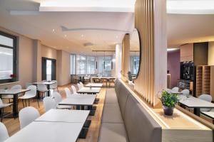 a restaurant with white tables and white chairs at B&B HOTEL Kassel-Wilhelmshöhe in Kassel