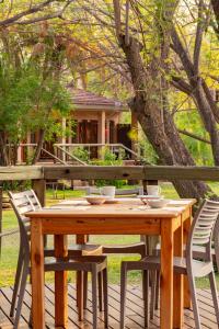 a wooden table and chairs on a deck with a tree at Sedia Hotel in Maun