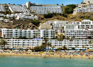 um grupo de pessoas numa praia com edifícios em El Greco em Puerto Rico de Gran Canaria