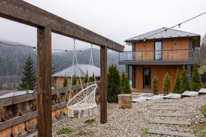 a swing in a yard next to a house at Agate Resort & SPA in Mykulychyn