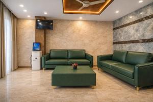a living room with two green couches and a table at Hotel Chalet, Madiwala in Bangalore