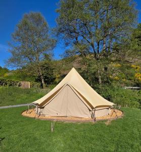 a tan tent sitting in the grass in a field at Camping Héiltzerstee in Rambrouch