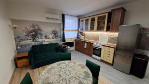 a kitchen with a green couch and a table in a kitchen at Tiszti Szálló Apartman in Verpelét