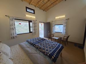 a bedroom with a bed and a table and windows at Ekatma Stays - Farm & Homestay, Kakrighat in Shitlakhet
