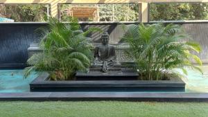 a statue of a buddha sits between two plants at Hotel Sriram JB Residency in Virudunagar