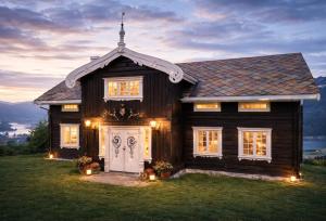 a wooden house with a white door in the grass at Traditional timber farm with Sauna & Wi-Fi in Baukål