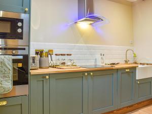 a kitchen with blue cabinets and a blue light at Dragonfly Cottage-Uk39919 in Ballakinnag
