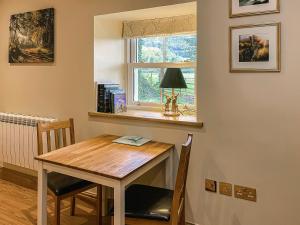 a dining room table and a window in a room at Dragonfly Cottage-Uk39919 in Ballakinnag