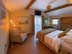 a bedroom with a bed and a chair at Dragonfly Cottage-Uk39919 in Ballakinnag +20 photos