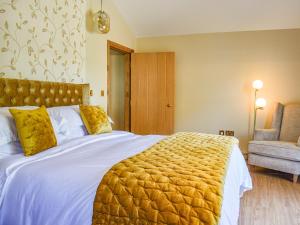 a bedroom with a large bed with a yellow blanket at Dragonfly Cottage-Uk39919 in Ballakinnag