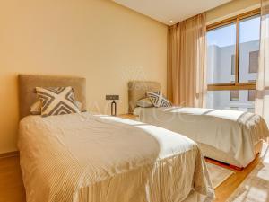 two beds in a room with a window at Iris Agadir - Luxe - Piscine - 4 Px in Agadir