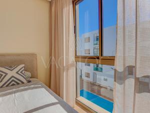 a bedroom with a window with a view of a building at Iris Agadir - Luxe - Piscine - 4 Px in Agadir +16 photos
