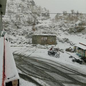 a person riding a motorcycle on a snow covered road at Snow Valley in Dhanaulti