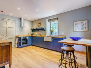 a large kitchen with blue cabinets and a wooden floor at East Lodge in Falkland +17 photos