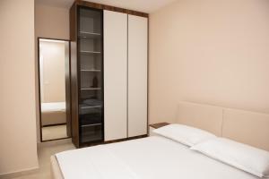 a bedroom with a white bed and a mirror at White Arena Apartments GOLEM in Golem
