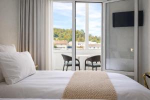 ein Hotelzimmer mit einem Bett und einem Tisch mit Stühlen in der Unterkunft Grand Hôtel d'Espagne in Lourdes