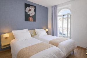 zwei Betten in einem Hotelzimmer mit Fenster in der Unterkunft Grand Hôtel d'Espagne in Lourdes