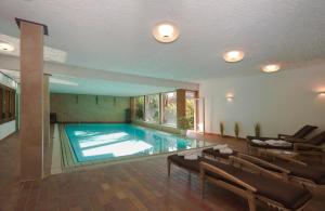 a large swimming pool in a large room with chairs at Ferienwohnungen St Hippolyt mit Hallenbad in Lagundo