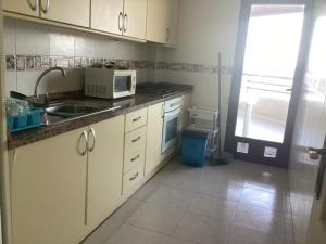 a kitchen with white cabinets and a sink and a microwave at Brisa Mediterránea II, Topacio IV in Ifach