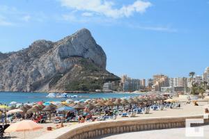 a beach with a bunch of umbrellas and a mountain at Brisa Mediterránea II, Topacio IV in Ifach