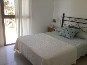 a bedroom with a white bed with a window at Brisa Mediterránea II, Topacio IV in Ifach +11 photos