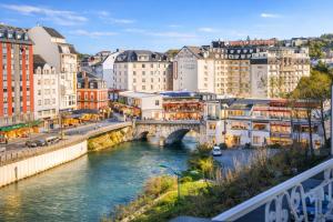 eine Brücke über einen Fluss in einer Stadt mit Gebäuden in der Unterkunft Grand Hôtel d'Espagne in Lourdes