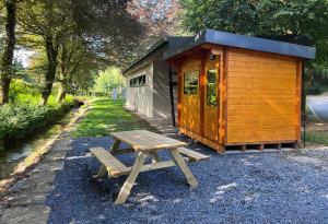 a wooden cabin with a picnic table next to it at Camping Héiltzerstee in Rambrouch +5 photos