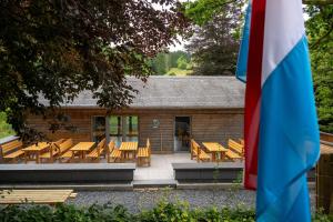 a group of wooden tables and chairs in front of a building at Camping Héiltzerstee in Rambrouch