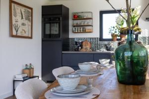 a table with plates and a green vase on it at Slapen bij Bioduin in Koudekerke