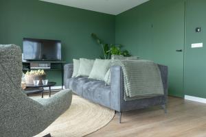 a living room with a couch and a chair at Slapen bij Bioduin in Koudekerke