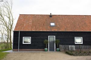 a black house with a red roof and a door at Slapen bij Bioduin in Koudekerke