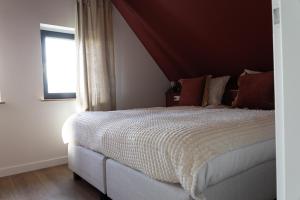 a bedroom with a large bed with a red ceiling at Slapen bij Bioduin in Koudekerke