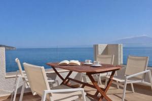a wooden table and chairs with a view of the ocean at 9 Muses Apartments in Agios Nikolaos +79 photos