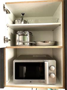 a microwave oven in a cabinet with some food at Charmant studio aux beaux volumes in Dreux