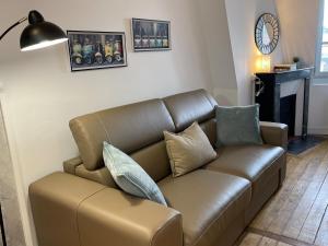 a brown leather couch in a living room with a fireplace at Charmant studio Hyper centre in Dreux