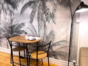 a table and chairs with a mural of palm trees at Charmant studio Hyper centre in Dreux